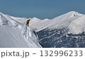 Skier evaluating snowy ridge line in mountain landscape 132996233