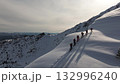 Adventurers climbing snowy mountain ridge in scenic winter landscape 132996240