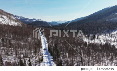 Snowy mountain road winding through serene winter landscape Snowy mountain road winding through serene winter landscape 132996249
