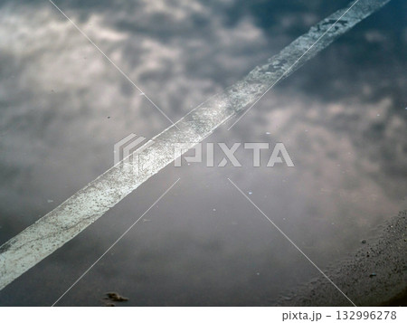 The reflection of the clouds and sky on the flood puddle on the road 132996278