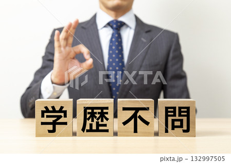 「学歴不問」と書かれたブロックとOKポーズをするビジネスマン 132997505