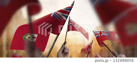 Bermuda flags in their hands on a blurred urban background 132998058