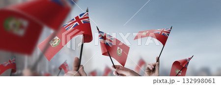 Bermuda flags in their hands on a blurred urban background 132998061