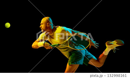 Energetic tennis player hitting forehand illuminated by cinematic lighting 132998161