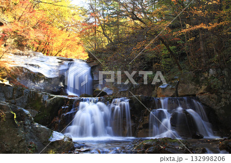 A waterfall in a valley colored with autumn leaves. A waterfall in a valley colored with autumn leaves. 132998206