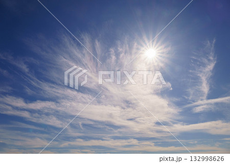 秋の空に輝く太陽と薄雲 132998626