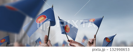 ASEAN flags in their hands on a blurred urban background 132998653