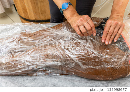 A therapist applies a luxurious chocolate or mud body wrap to a person A therapist applies a luxurious chocolate or mud body wrap to a person 132998677
