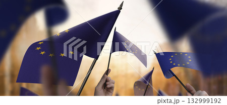 European Union flags in their hands on a blurred urban background European Union flags in their hands on a blurred urban background 132999192