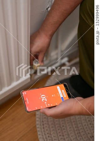 Smartphone connecting to heating radiator. Remote home control system on a smartphone. Smartphone connecting to heating radiator. Remote home control system on a smartphone. 132999496