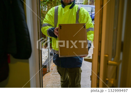 Delivery man at door entrance giving a box to a woman. Online shopping, delivery service 132999497