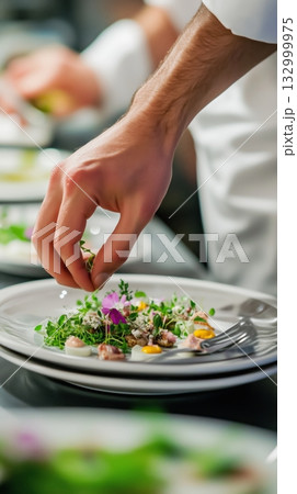 Chef Garnishes a Fine Dish With Fresh Herbs and Edible Flowers in a Restaurant Kitchen Chef Garnishes a Fine Dish With Fresh Herbs and Edible Flowers in a Restaurant Kitchen 132999975