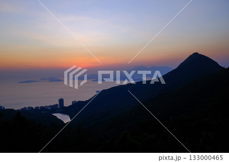 The seascape at sunset with ships and cityscape in the background. Sun-rays reflected on the calm sea. Sea background and cityscape. Nature concept. 133000465