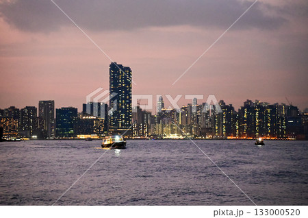 The seascape at sunset with ships and cityscape in the background. Sun-rays reflected on the calm sea. Sea background and cityscape. Nature concept. 133000520