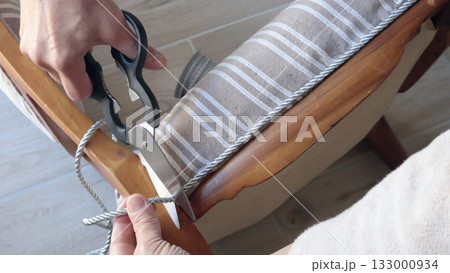 Anonymous person cut decorative braid with scissors. Antique furniture restoration. Crafts and hobbies. 133000934