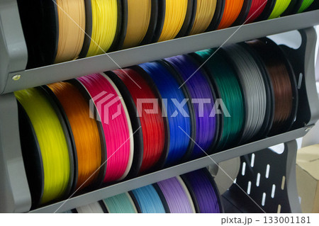 Many spools with multi-colored plastic for 3D printing. Spools with pink, red, burgundy, purple blue plastic wire for 3D printer. Components for 3D printing. Accessories for 3D printer. FDM technology 133001181