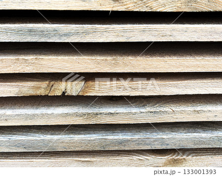 A close-up of stacked wooden planks with a natural grain pattern. Wooden planks stacked. A close-up of stacked wooden planks with a natural grain pattern. Wooden planks stacked. 133001393