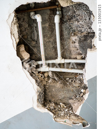view of plastic pipework in hole of broken wall 133001915