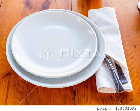 empty white plates and knife and fork in napkin empty white plates and knife and fork in napkin 133002035