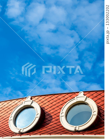 blue sky above round porthole windows in red roof blue sky above round porthole windows in red roof 133002202