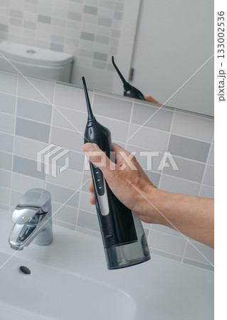 close view of a man lifting an oral irrigator close view of a man lifting an oral irrigator 133002536