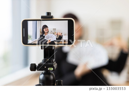 Caucasian young woman blogging about financial topics in office environment holding dollar bills. Talking to camera discussing economic strategies and finance concepts, encouraging viewers Caucasian young woman blogging about financial topics in office environment holding dollar bills. Talking to camera discussing economic strategies and finance concepts, encouraging viewers 133003553