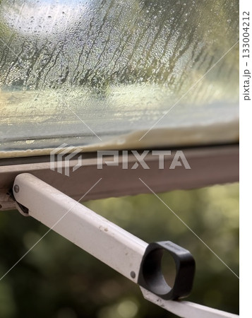 Rainy day seen through open window with raindrops on glass, creating natural background 133004212