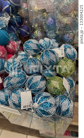 Christmas ornaments displayed in a store, featuring blue, silver, and green glitter designs 133004225