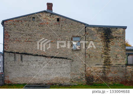 Old weathered brick wall of abandoned building with cracks and damaged window in urban area 133004688