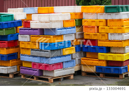 Colorful plastic fish boxes stacked on wooden pallets in a harbor storage area Colorful plastic fish boxes stacked on wooden pallets in a harbor storage area 133004691