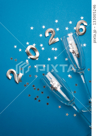 New Year 2026 Champagne Flutes with Silver Confetti on Blue Background New Year 2026 Champagne Flutes with Silver Confetti on Blue Background 133005246
