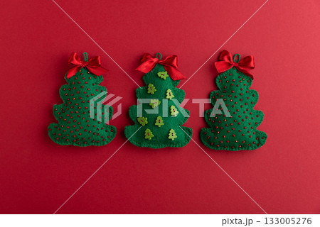 Handmade Felt Christmas Tree Ornaments with Bows on Red Background Handmade Felt Christmas Tree Ornaments with Bows on Red Background 133005276