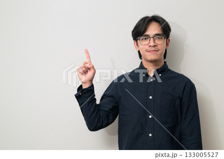 Young Asian businessman wearing eyeglasses pointing and showing copy space against white background 133005527