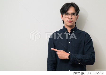 Portrait of handsome young Asian Thai man wearing eyeglasses showing copy space with hand gesture 133005537