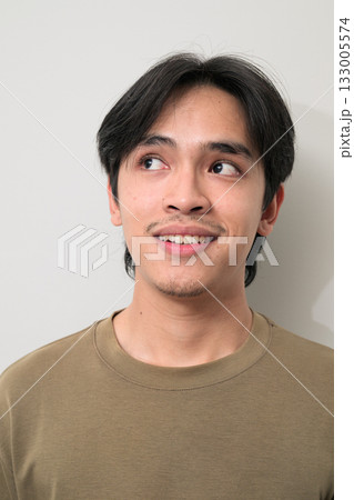 Portrait of handsome Young Asian Thai man smiling and thinking against white background 133005574
