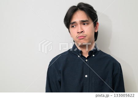 Portrait of handsome Young Asian Thai man looking sad while thinking against white background Portrait of handsome Young Asian Thai man looking sad while thinking against white background 133005622