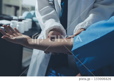 Doctor examining patient's elbow in hospital room 133006826