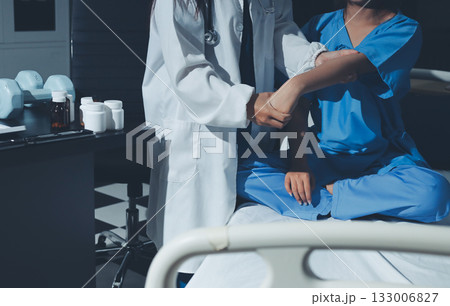 Doctor examining patient's elbow in hospital room Doctor examining patient's elbow in hospital room 133006827
