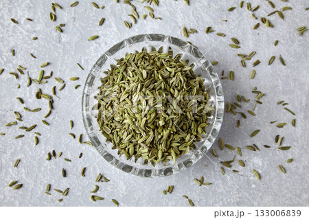 Fennel in a crystal bowl scattered on a gray concrete table, top view. Fennel in a crystal bowl scattered on a gray concrete table, top view. 133006839