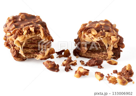 Close-up of a broken wafer caramel bar with nuts in chocolate glaze on a white background/ Close-up of a broken wafer caramel bar with nuts in chocolate glaze on a white background/ 133006902