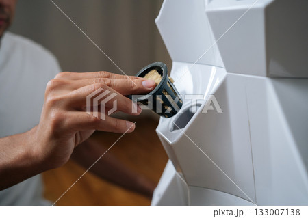 Close-up of male hands placing rockwool cube inside net pot, inserting it into hydroponic tower system, preparing for seed starting and modern agriculture. Concept of home gardening. Close-up of male hands placing rockwool cube inside net pot, inserting it into hydroponic tower system, preparing for seed starting and modern agriculture. Concept of home gardening. 133007138