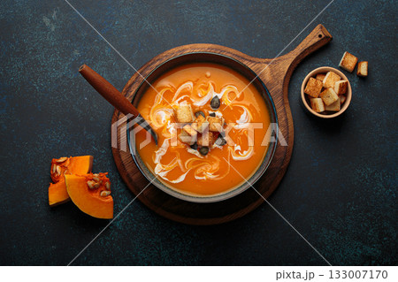 Pumpkin soup croutons cream fresh pumpkin slices wooden board dark background autumn winter 133007170