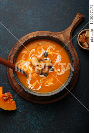 Pumpkin soup croutons cream fresh pumpkin slices wooden board dark background autumn winter 133007173