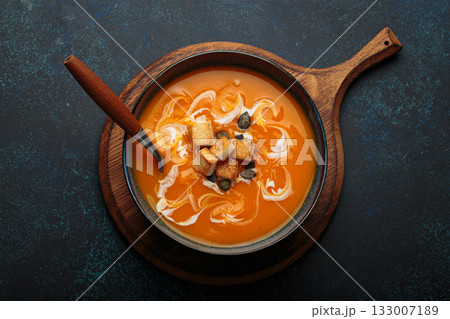 Pumpkin soup croutons cream fresh pumpkin slices wooden board dark background autumn winter Pumpkin soup croutons cream fresh pumpkin slices wooden board dark background autumn winter 133007189
