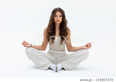 Woman meditating peacefully, Serene female in calm meditation, Young lady practicing mindfulness in studio, Graceful woman with curly hair engaged in breathwork Woman meditating peacefully, Serene female in calm meditation, Young lady practicing mindfulness in studio, Graceful woman with curly hair engaged in breathwork 133007378