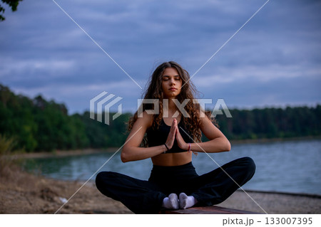 Engaging in Peaceful Meditation by the Tranquil Lake during the Beautiful Dusk Hours Engaging in Peaceful Meditation by the Tranquil Lake during the Beautiful Dusk Hours 133007395