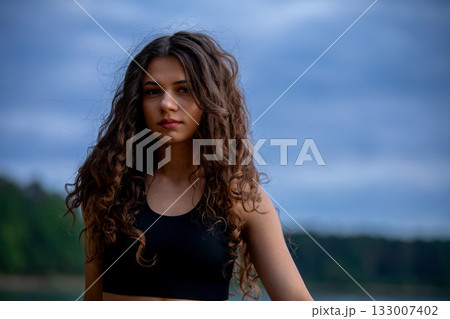 A Young Woman Poses Beautifully by Water with Her Gorgeous Curls A NatureInspired Fashion Shoot A Young Woman Poses Beautifully by Water with Her Gorgeous Curls A NatureInspired Fashion Shoot 133007402