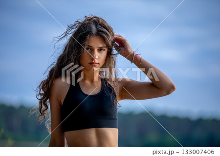 A Young Woman in a Sporty Pose by the Beautiful Water, Radiating Confidence and Energy 133007406