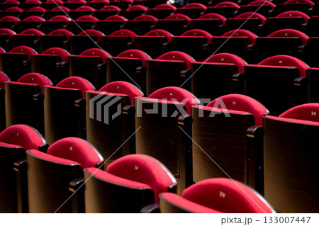 Elegant Red Theatre Seats Arranged in Neat Rows for an Upscale Audience Experience Elegant Red Theatre Seats Arranged in Neat Rows for an Upscale Audience Experience 133007447