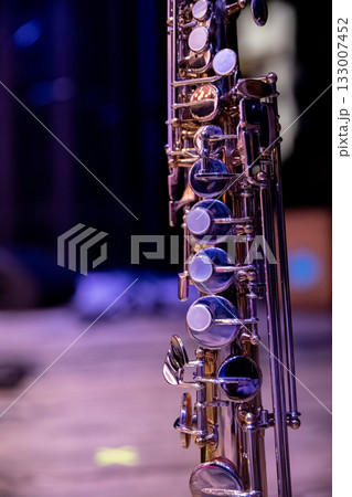 A CloseUp of a Sleek and Shiny Silver Saxophone Set Against a Softly Dim Background A CloseUp of a Sleek and Shiny Silver Saxophone Set Against a Softly Dim Background 133007452